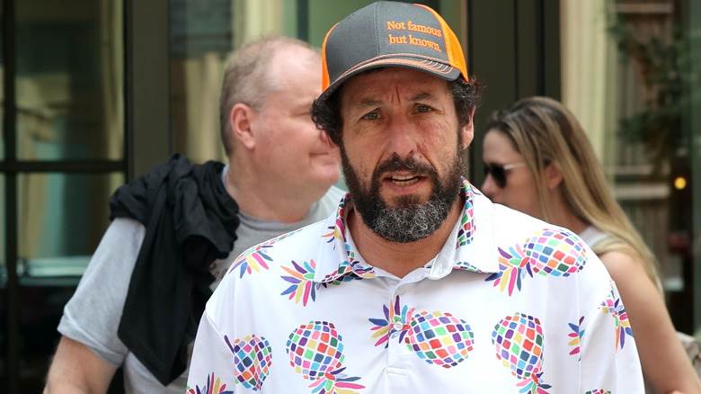 Adam Sandler debout sur le trottoir