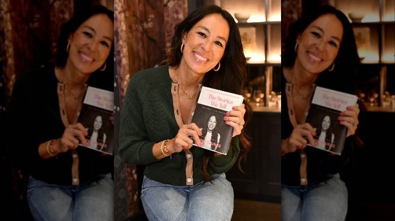 Joanna Gaines sourit en tenant son livre