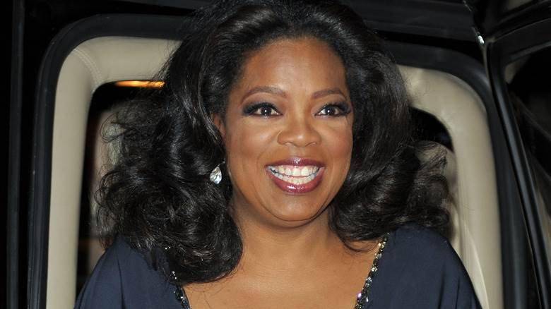 Oprah Winfrey souriante dans un haut bleu marine