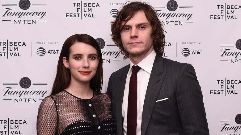 Emma Roberts et Evan Peters sourient bouche bée en regardant la caméra