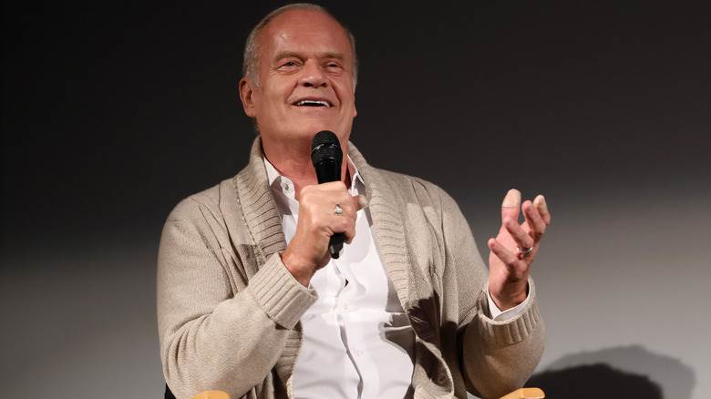 Kelsey Grammer assise sur une chaise et parlant sur scène