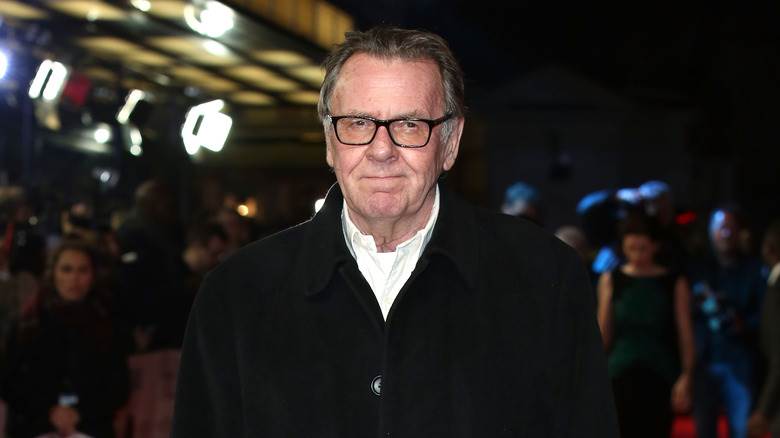 Tom Wilkinson posant en noir