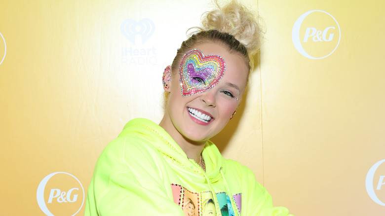 JoJo Siwa souriant avec un cœur arc-en-ciel autour des yeux