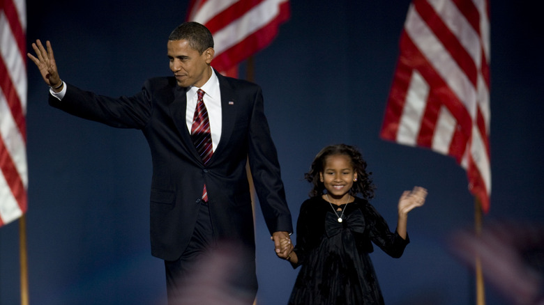 Barack Obama et sa jeune fille Sasha devant des drapeaux