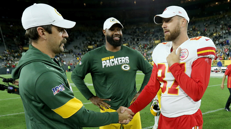 Travis Kelce et Aaron Rodgers se serrent la main sur un terrain de football