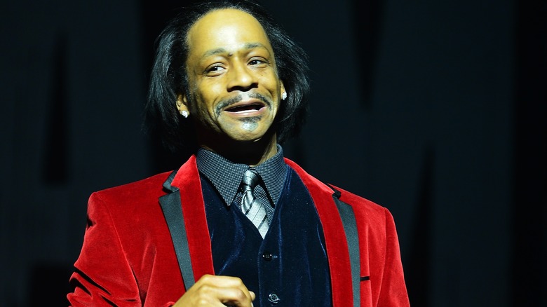 Katt Williams s'exprimant sur scène en blazer rouge