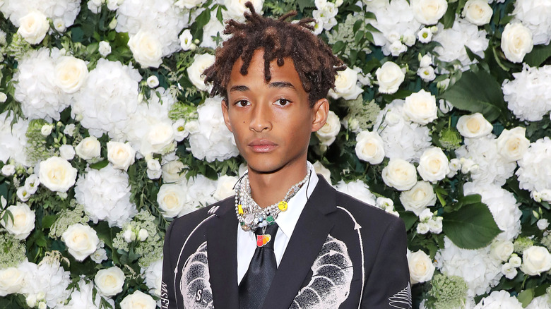 Jaden Smith devant un mur de fleurs