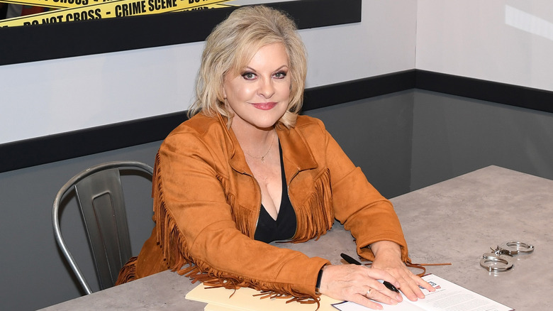 Nancy Grace souriante et assise à une table