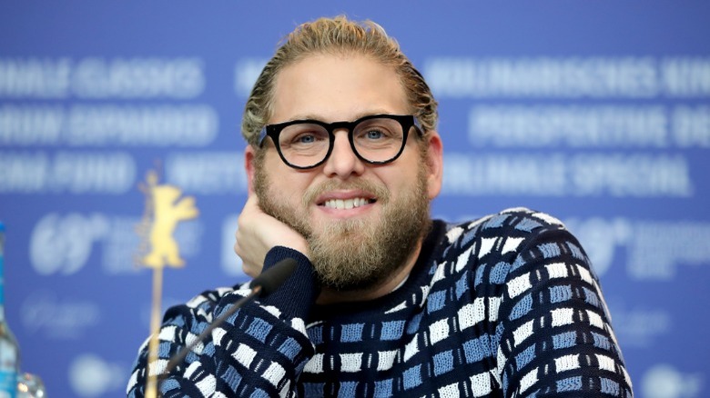 Jonah Hill souriant dans un pull bleu