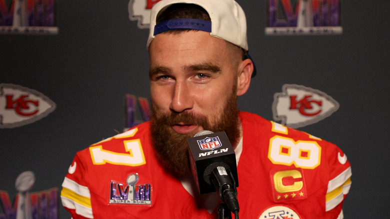 Travis Kelce souriant en gros plan avec un microphone