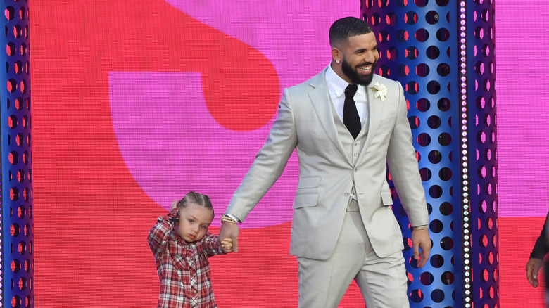 Drake sourit en tenant son fils dans ses bras