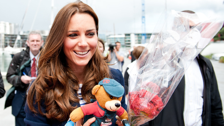 Kate Middleton tenant un ours et des fleurs