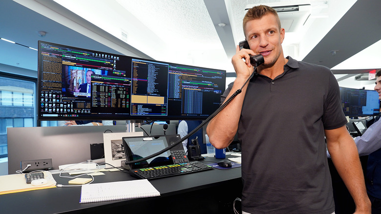 Rob Gronkowski portant un polo gris tout en parlant au téléphone