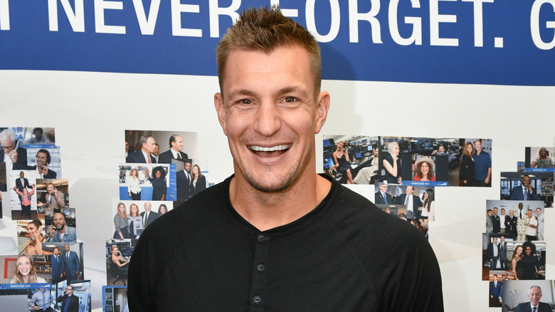 Rob Gronkowski souriant portant un t-shirt noir boutonné