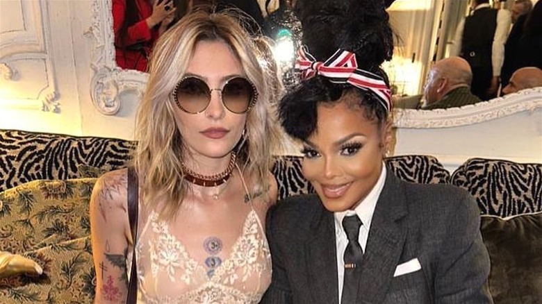 Paris Jackson porte un débardeur en dentelle et des lunettes de soleil avec Janet Jackson portant une veste noire, une chemise blanche et une cravate noire