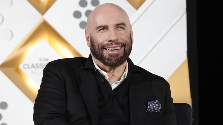 John Travolta assis et souriant