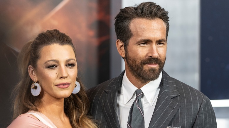 Blake Lively porte une robe blanche et de grandes créoles et Ryan Reynolds porte un costume gris à rayures