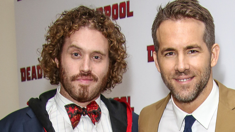 TJ Miller portant une veste bleue, une chemise blanche et un nœud papillon rouge avec Ryan Reynolds portant un costume beige et une chemise blanche