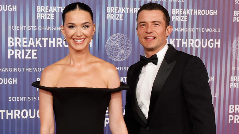 Katy Perry porte une robe noire et Orlando Bloom porte un smoking noir