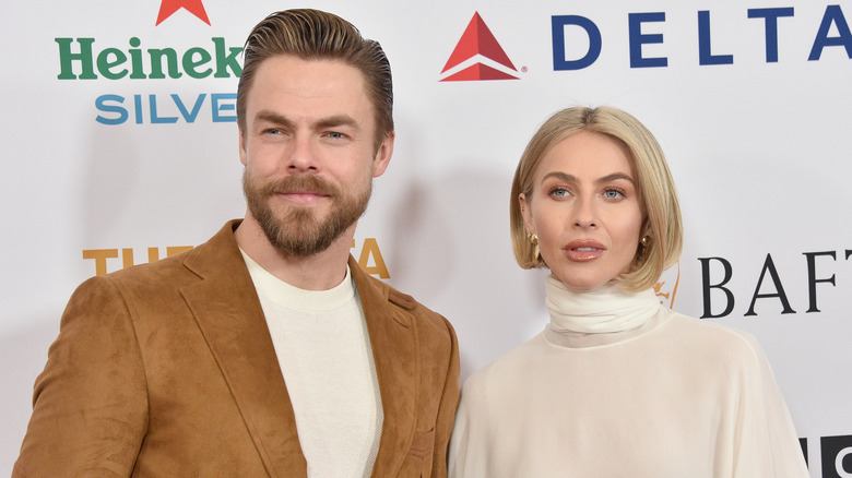 Derek Hough porte une veste en daim marron et une chemise blanche avec Julianne Hough portant un col roulé crème