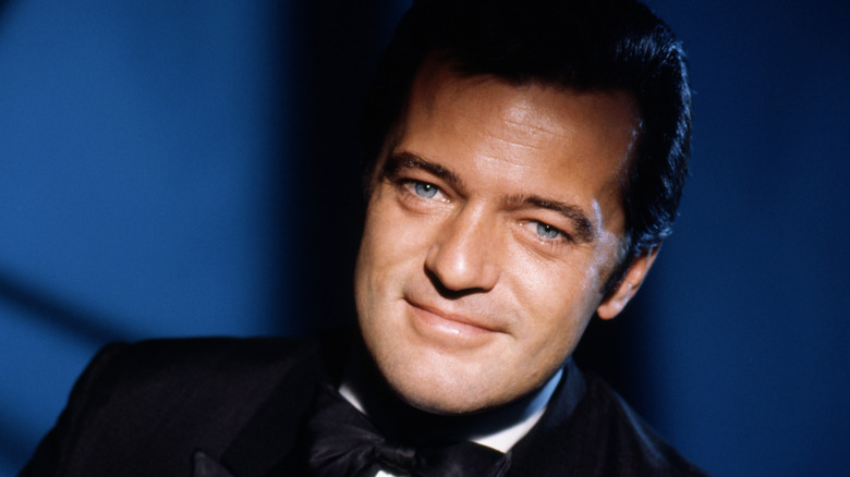 Robert Goulet souriant en smoking sur fond bleu