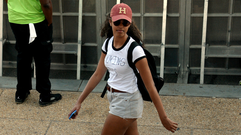 Malia Obama porte un t-shirt blanc, un short en jean et une casquette rouge