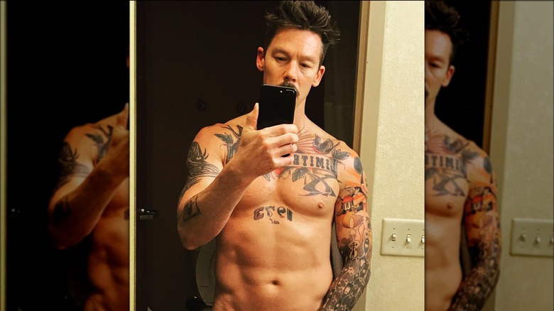 David Bromstad torse nu regardant son téléphone