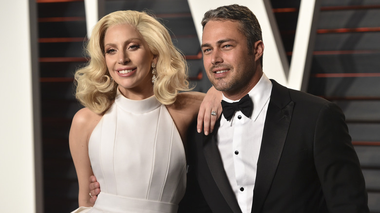 Lady Gaga portant une robe blanche et une bague en diamant, tandis que Taylor Kinney porte un smoking et un nœud papillon.