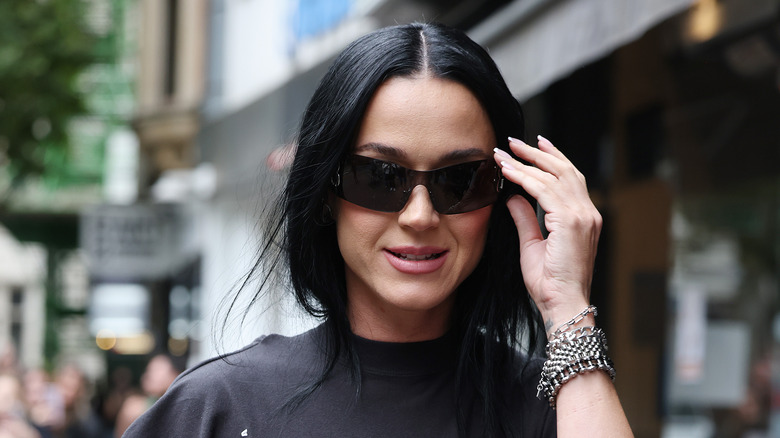 Katy Perry portant un t-shirt noir et des lunettes de soleil noires dans la rue