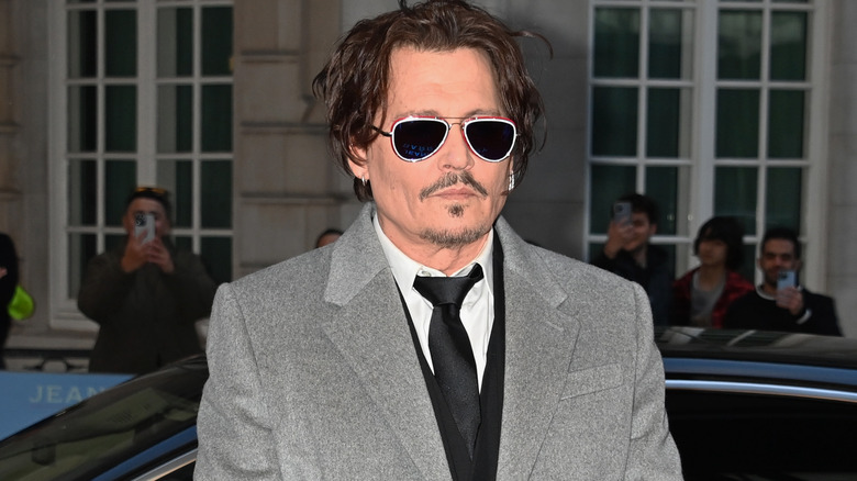 Johnny Depp portant des lunettes de soleil dans un pardessus gris