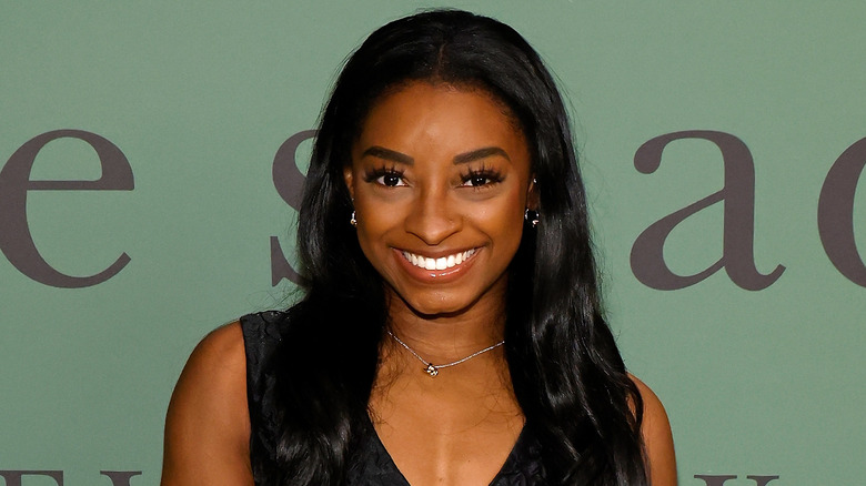 Simone Biles souriante en robe noire