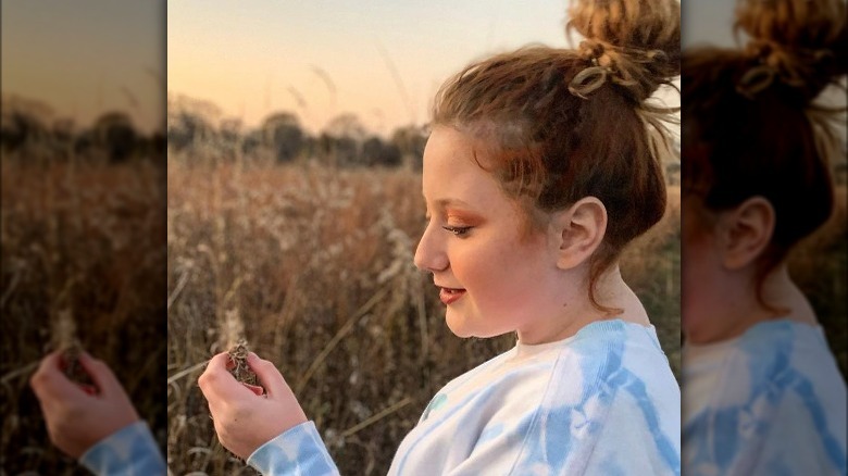 Bailee Ann sourit et regarde une fleur