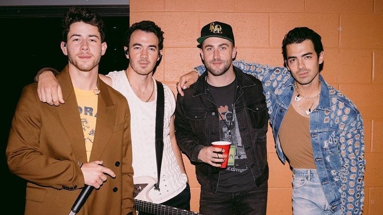 Nick Jonas, Kevin Jonas, Jordan McGraw et Joe Jonas en tenue de scène posant dans les coulisses