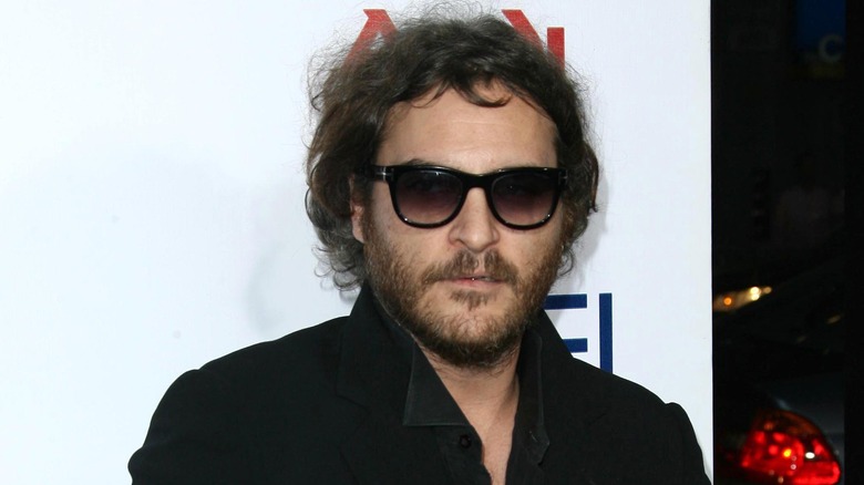 Joaquin Phoenix portant des lunettes de soleil noires et une veste noire