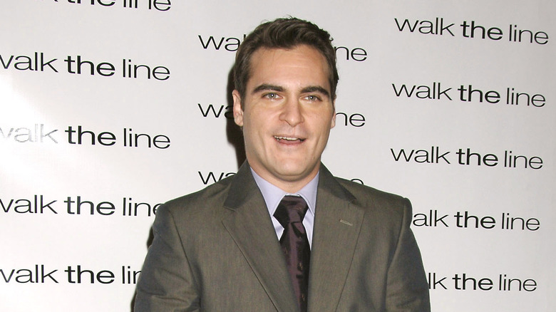 Joaquin Phoenix portant un costume gris et une cravate violette sur le tapis rouge