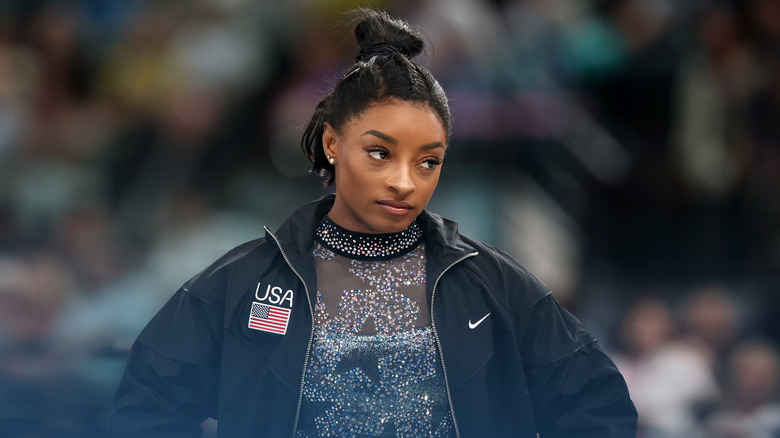 Simone Biles porte un justaucorps étincelant et une veste Nike noire USA