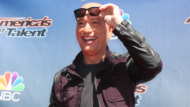 Howie Mandel souriant et ajustant les lunettes