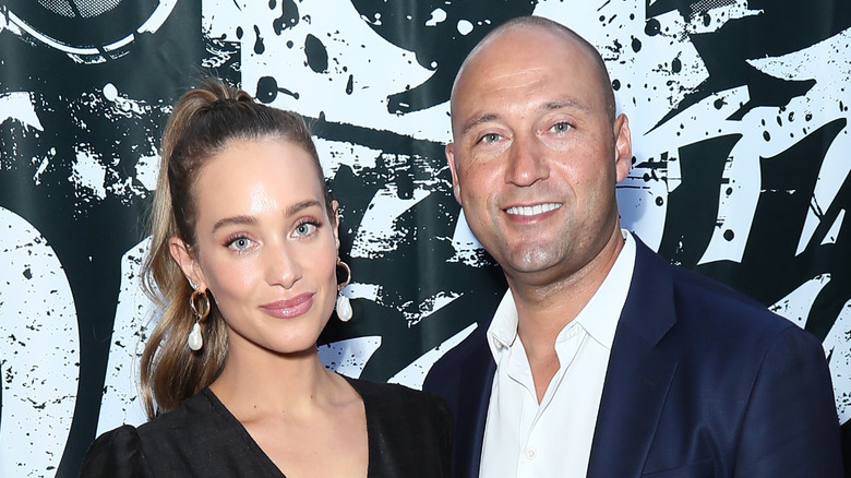 Derek et Hannah Jeter posent pour des photos devant un fond en noir et blanc.