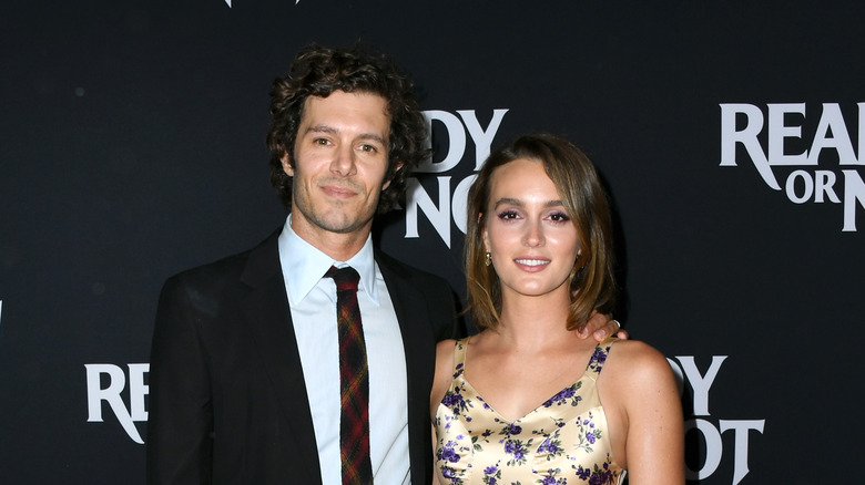 Adam Brody en costume noir ; Leighton Meester en robe à fleurs jaune