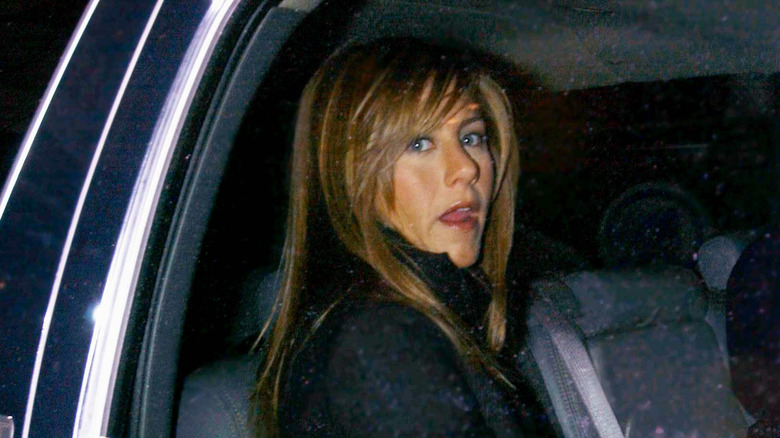 Jennifer Aniston dans une limousine portant une veste noire sur une photo paparazzi