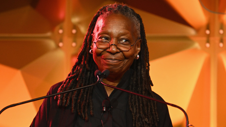 Whoopi Goldberg sourit devant un podium