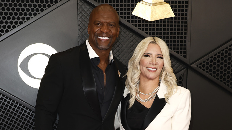 Terry Crews et Rebecca King-Crews sourient avec des dents et portent des tenues en noir et blanc