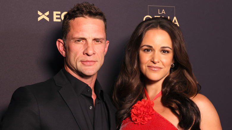 David Fumero portant un smoking noir ; Melissa Fumero à côté de lui dans une robe rouge avec des détails floraux