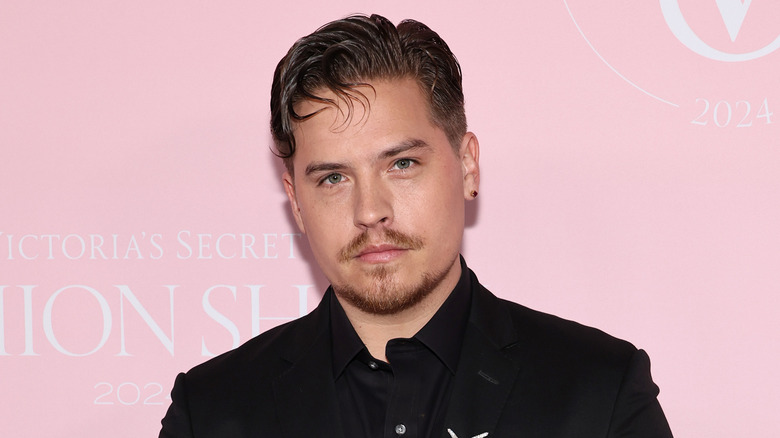 Dylan Sprouse aux cheveux gélifiés portant une veste à col noir