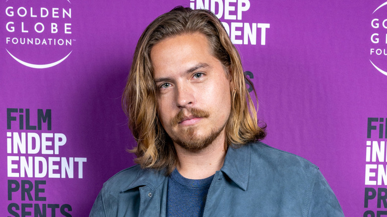 Dylan Sprouse porte une chemise en jean bleue et un t-shirt bleu en dessous