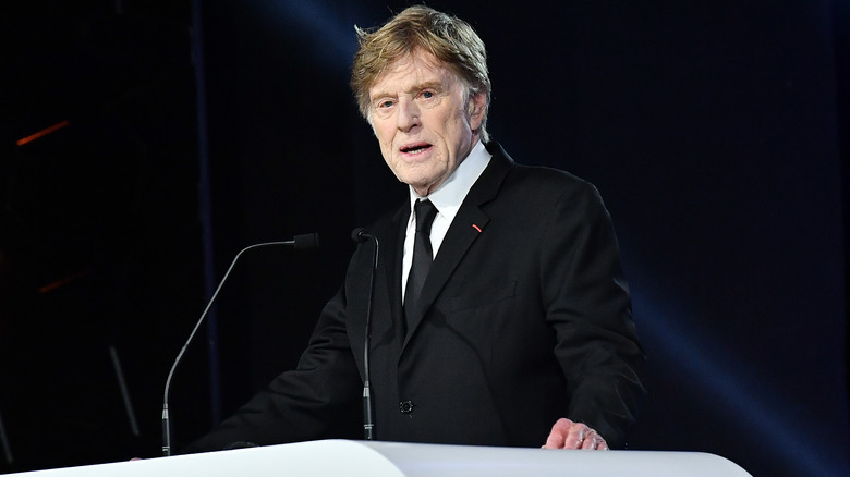 Robert Redford portant un costume debout sur un podium