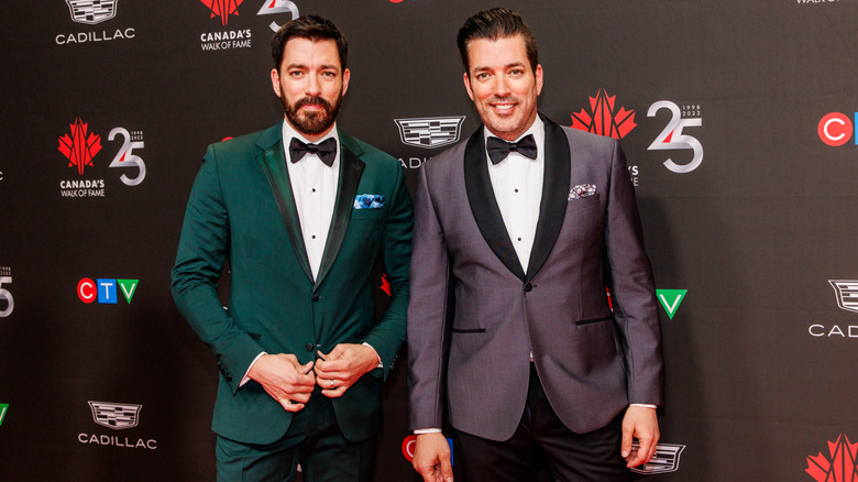 Les Property Brothers posant sur le tapis rouge dans des vestes vertes et violettes avec des nœuds papillons