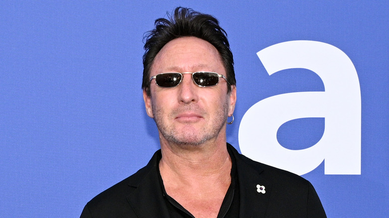 Julian Lennon portant une chemise boutonnée noire et des lunettes de soleil noires