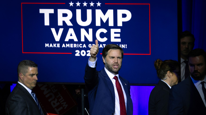 JD Vance lève le pouce devant le panneau Trump/Vance