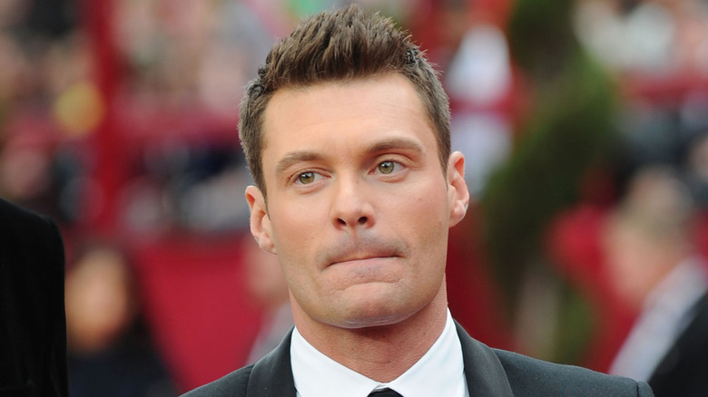 Ryan Seacrest se tient sur le tapis rouge dans un costume sombre